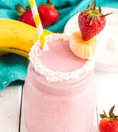 Overhead of a Coconut Strawberry Banana Smoothie garnished with coconut and fresh strawberries and bananas.