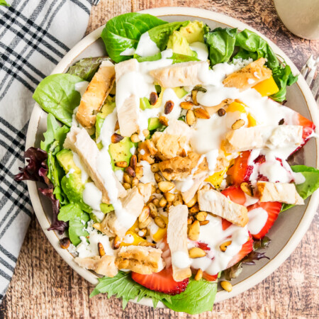 Overhead horizontal image of grilled chicken salad with strawberries and mango