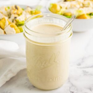 Healthy Caesar Dressing in a glass jar with a spoon in it.