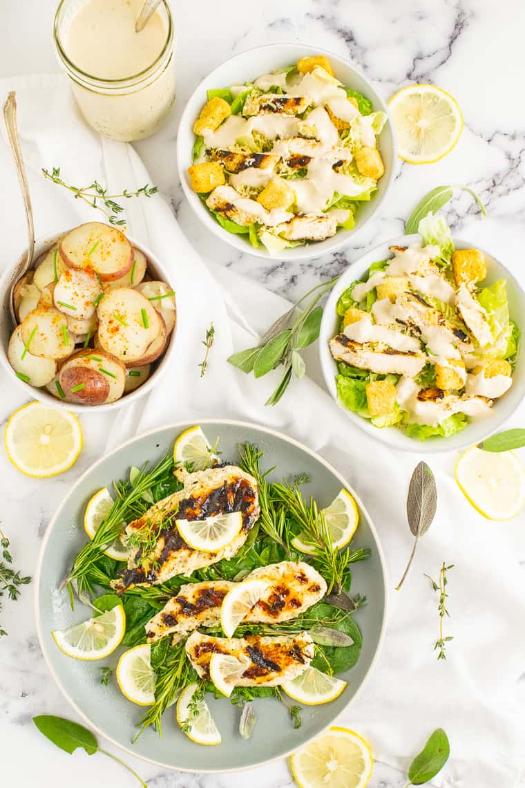 A dinner featuring lemon herb grilled chicken, caesar salad, and potatoes