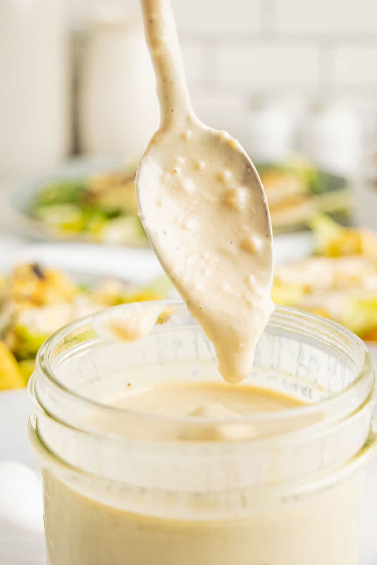 Creamy salad dressing dripping off a spoon