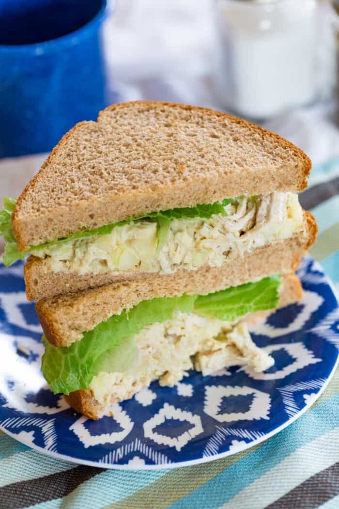 Two halves of a Chicken Salad Sandwich stacked on a white and blue patterned plate