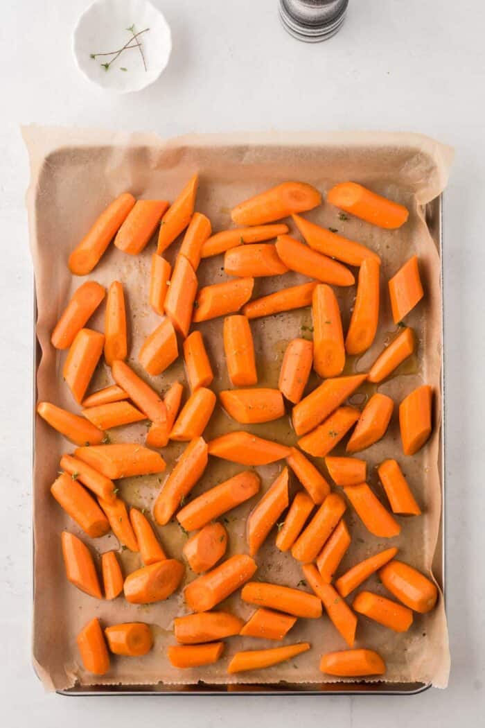 Raw carrots on a baking sheet with parchment paper to go into the oven