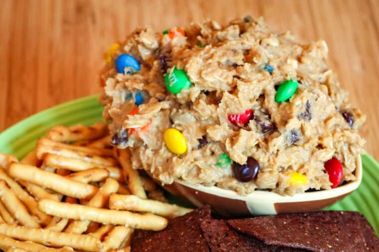 Edible Peanut Butter M&M's Cookie Dough in a bowl shaped like a football surrounded by pretzels and chips.