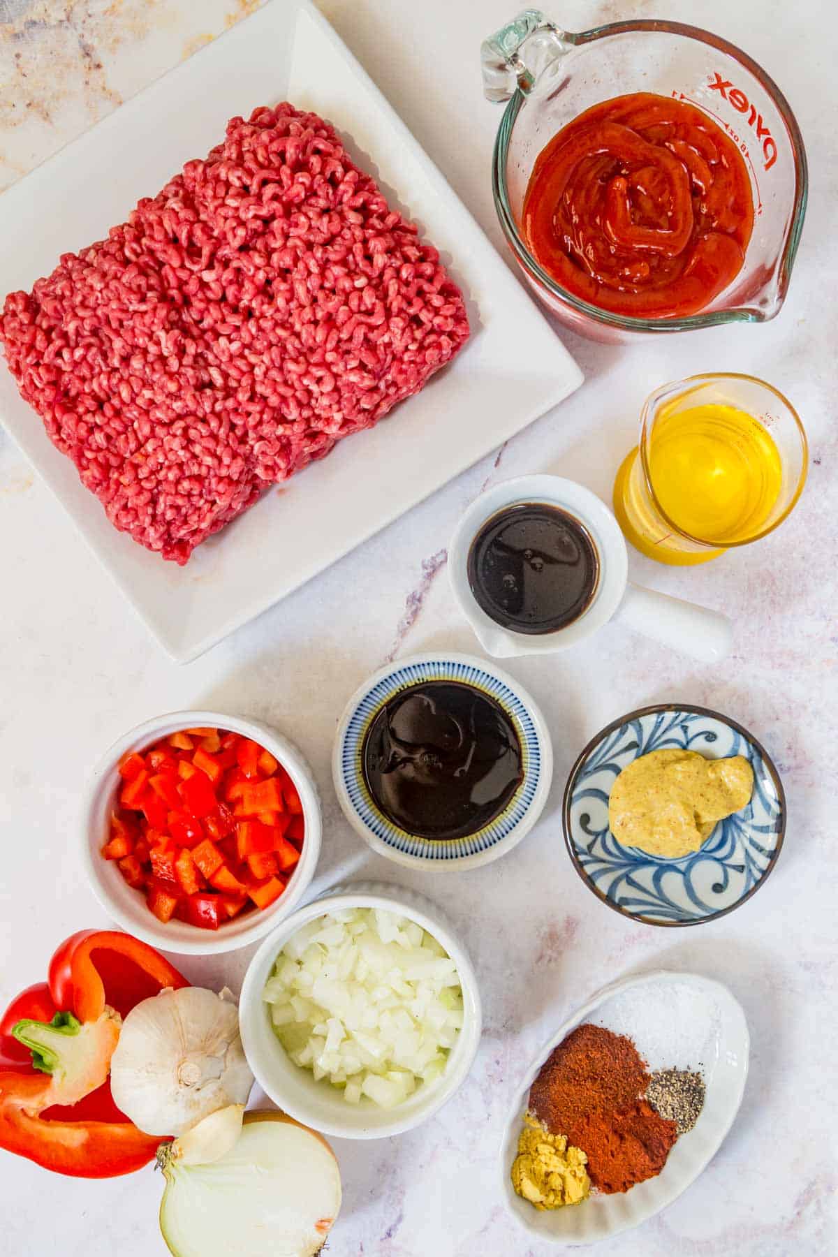 Ingredients to make homemade sloppy joes on a marble countertop.