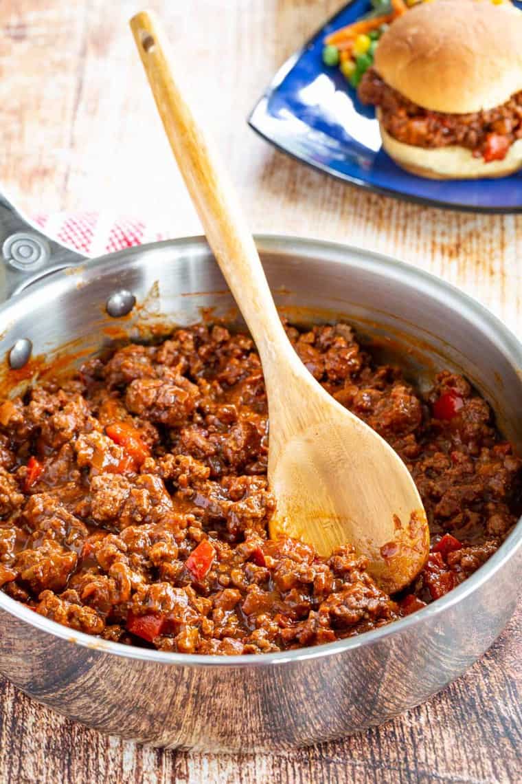 Sloppy Joe mixture in a skillet with a sandwich in the background