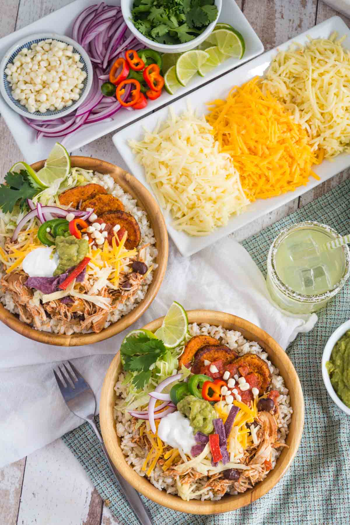 A Chicken Rice Bowl and a Cauliflower Rice Bowl with plates and bowls of fixings.