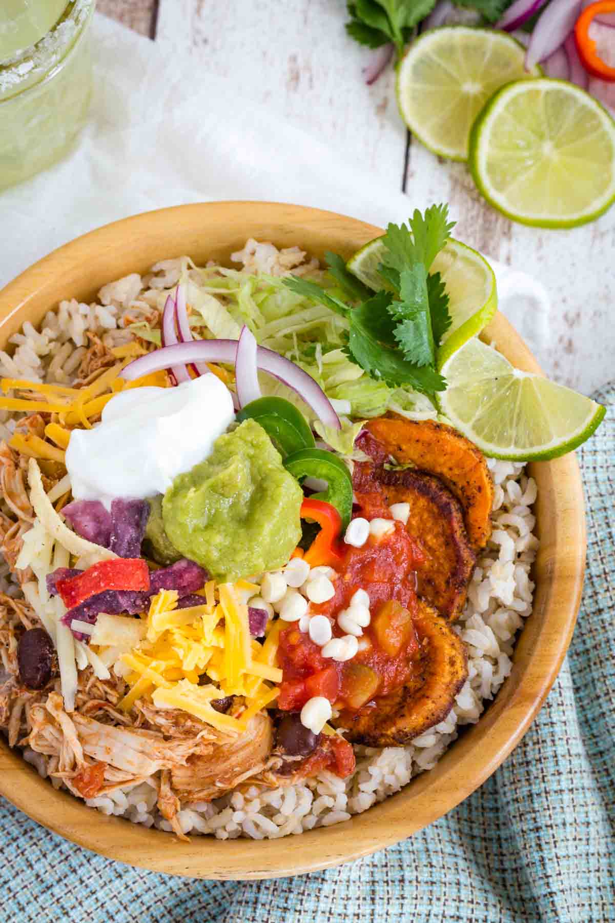 Salsa Chicken Rice Bowl with cheese, corn, tortilla chips, lime, lettuce and more on top