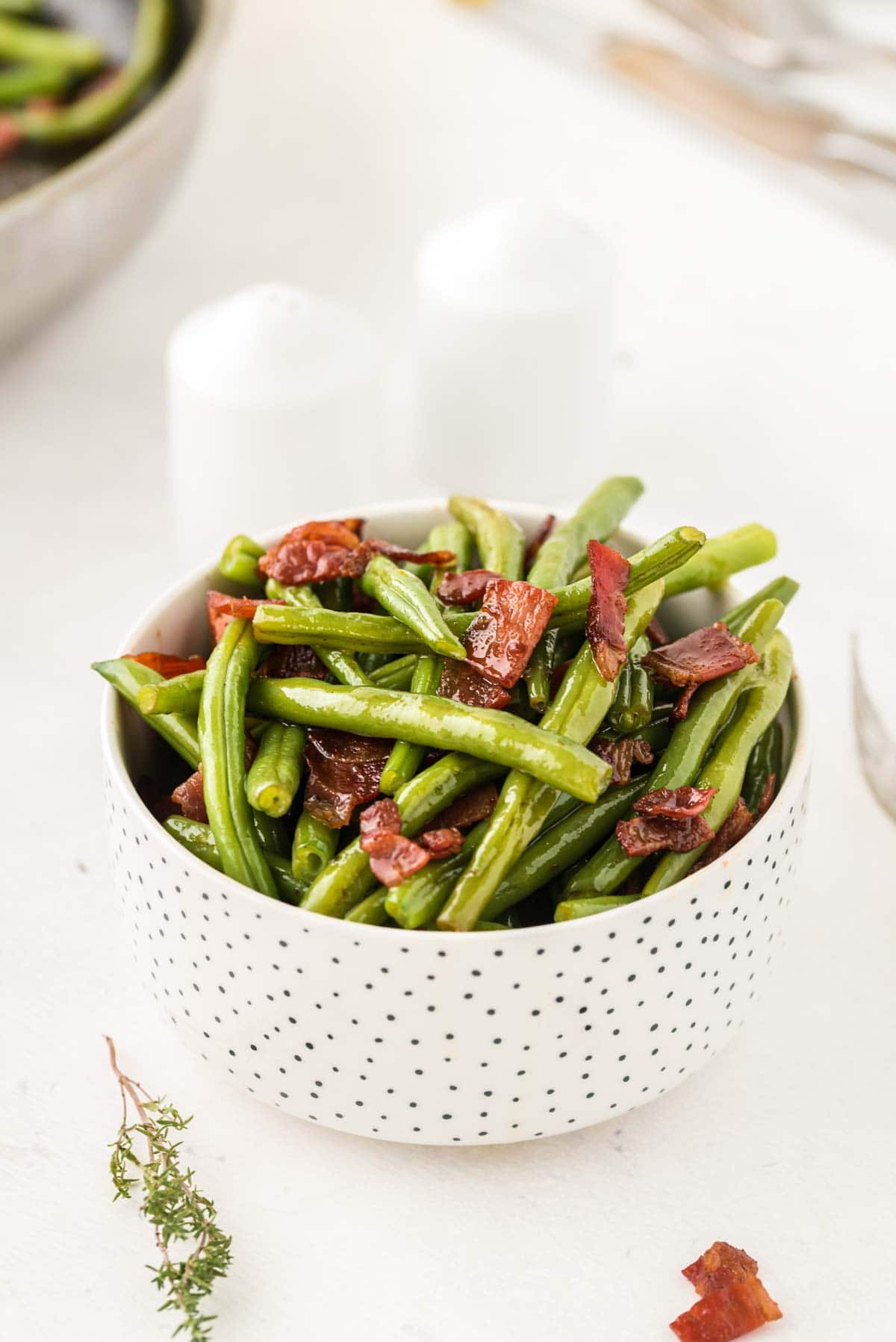 Small white serving bowl of green beans with bacon.