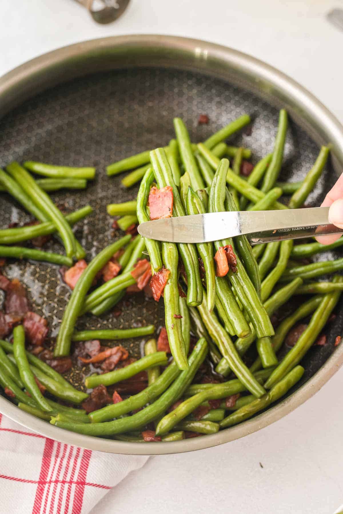 Tongs picking up Bacon Green Beans.