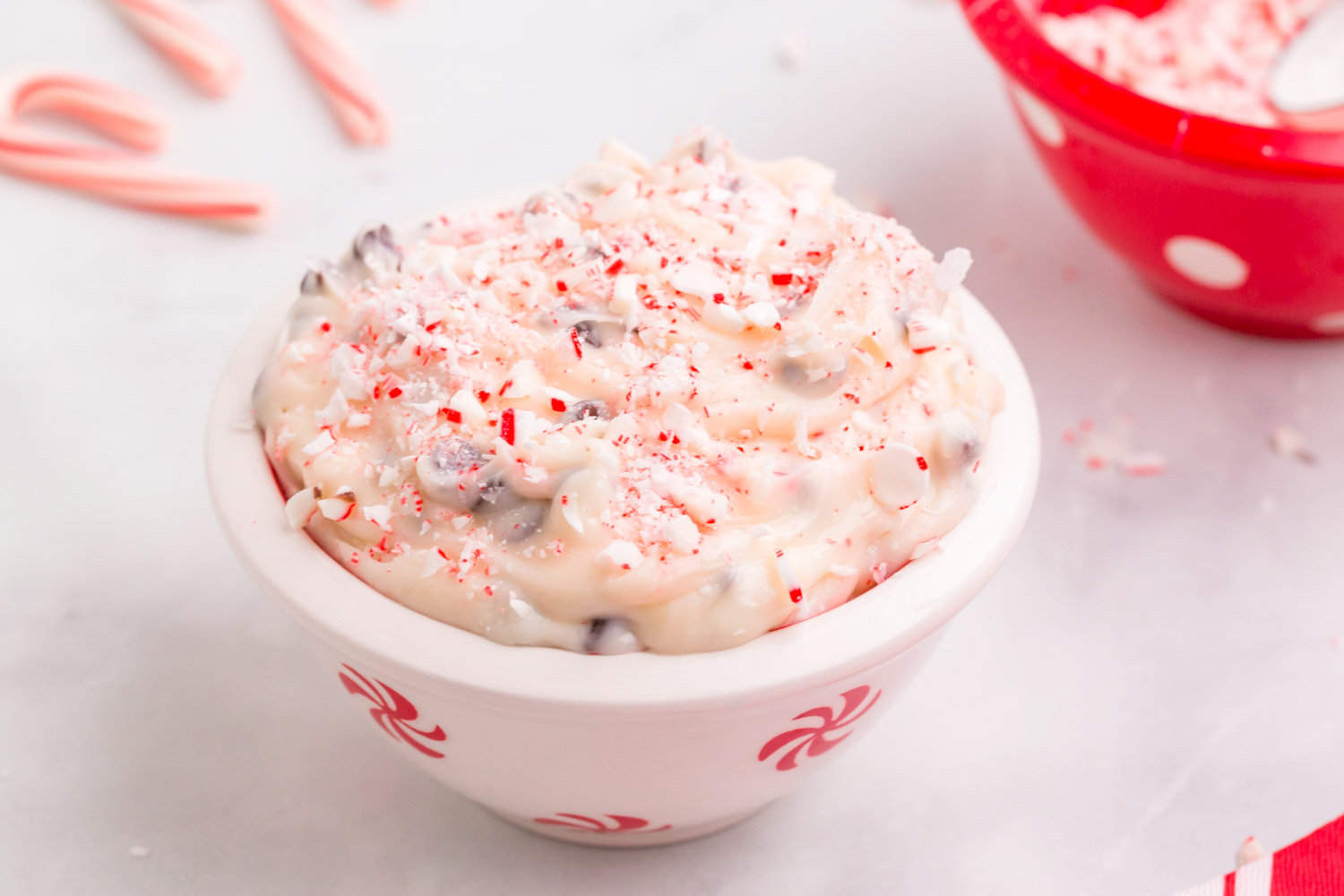 A small bowl of cheesecake dip with crushed candy canes on top.