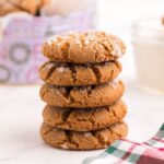 A stack of five gluten free gingersnaps in front of a cookie tin