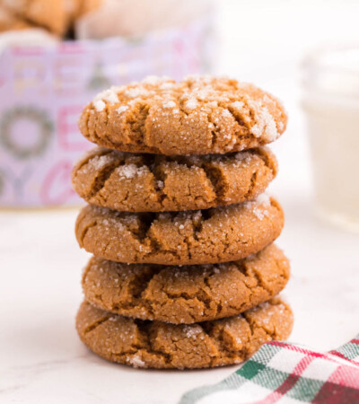 A stack of five gluten free gingersnaps in front of a cookie tin