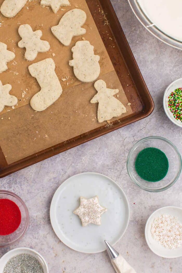 Piping bag next to a star-shaped Chai cookie decorated with white icing and silver sprinkles