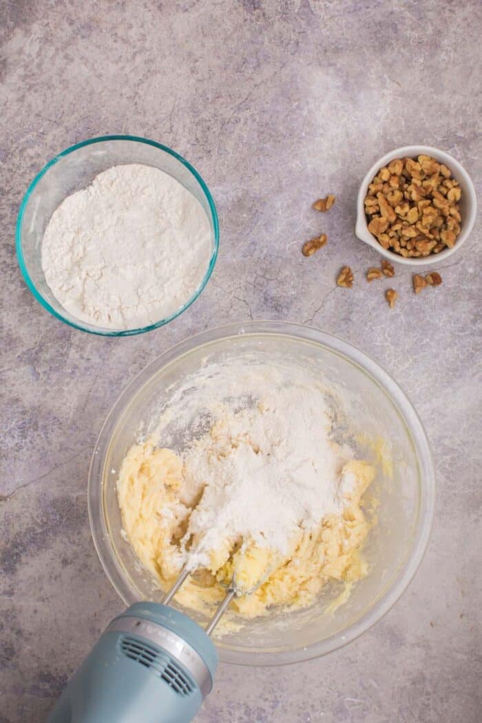 Some of the flour added to the bowl of creamed butter and sugar