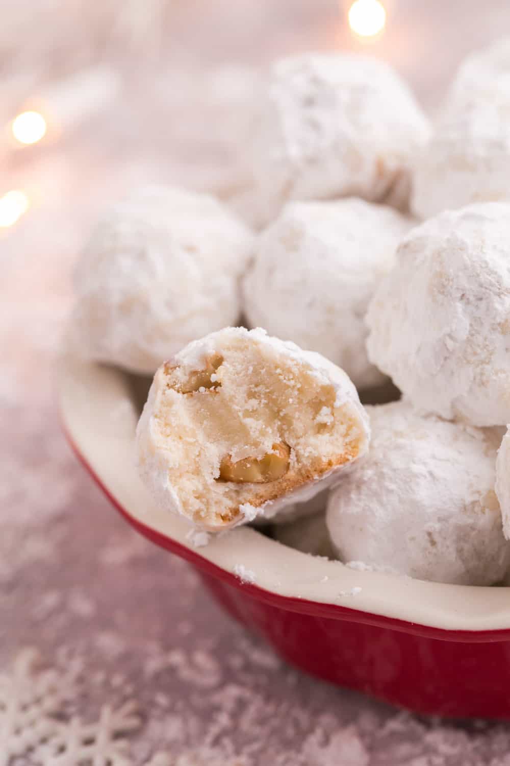 Gluten Free Snowball Cookies in a red dish with one with a bite taken out