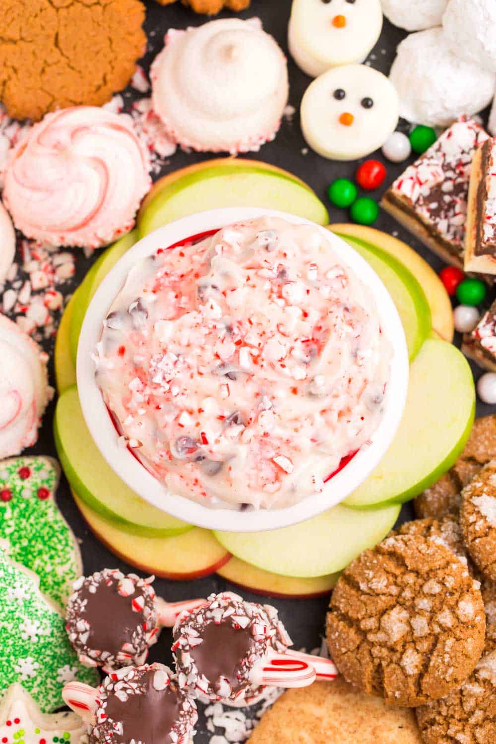 A platter of cookies with a bowl of peppermint chocolate chip cheesecake dip in the middle