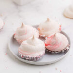 Four peppermint meringues with a red swirl on a white plate