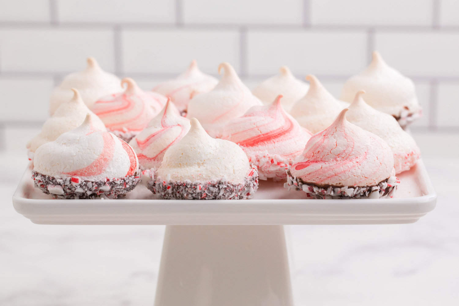 A square cake stand filled with peppermint meringues