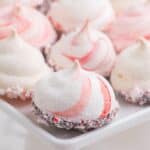 Four peppermint meringue cookies on a small white plate