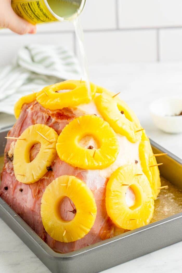 Pouring pineapple from a can oven the unbaked ham
