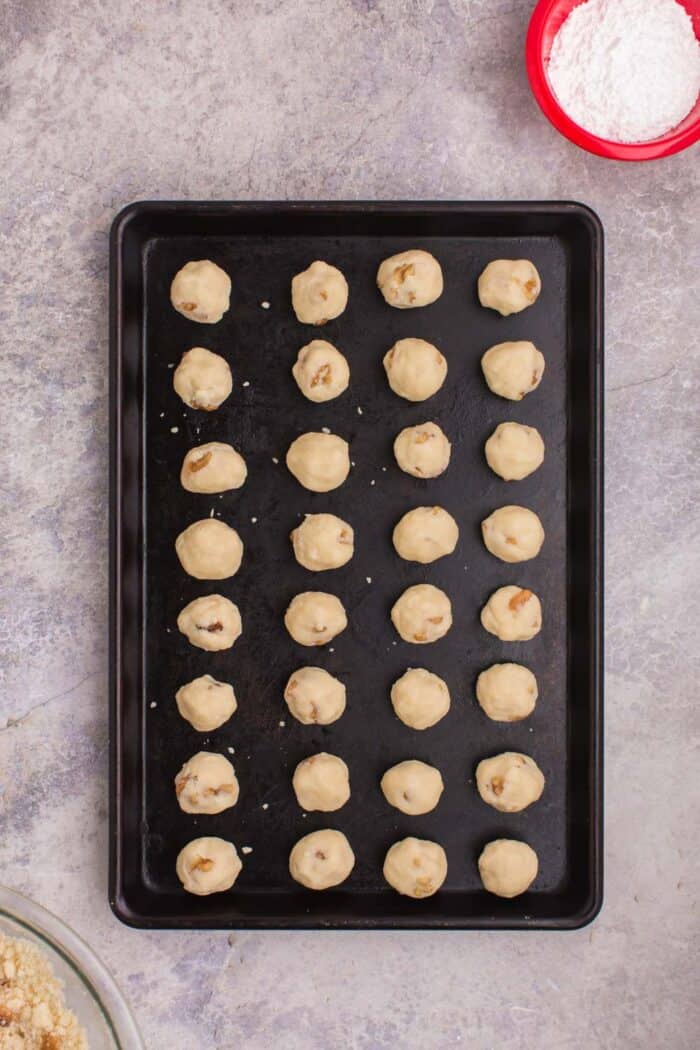 raw balls of snowball cookie dough on a baking sheet