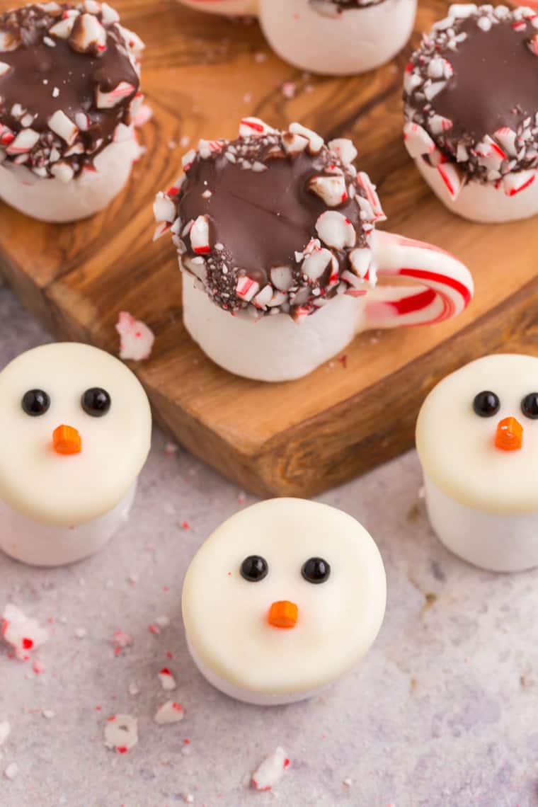 Marshmallows dipped in white and dark chocolate and decorated like snowmen and mugs of cocoa