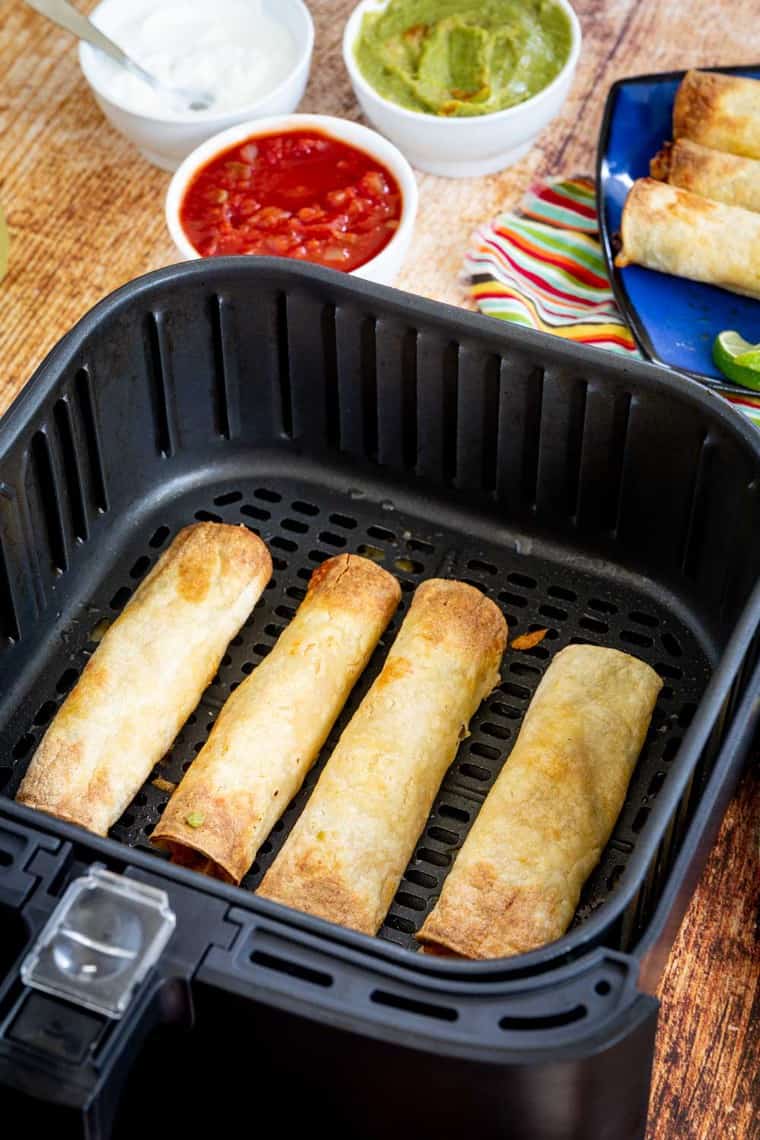 Cooked chicken taquitos in an air fryer basket