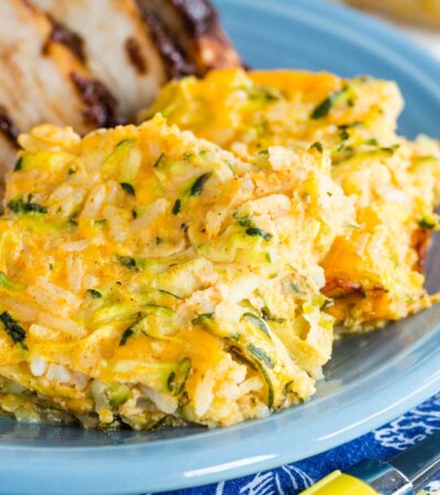 Zucchini casserole served as a side dish with chicken on a blue plate