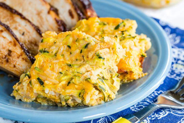 Zucchini casserole served as a side dish with chicken on a blue plate