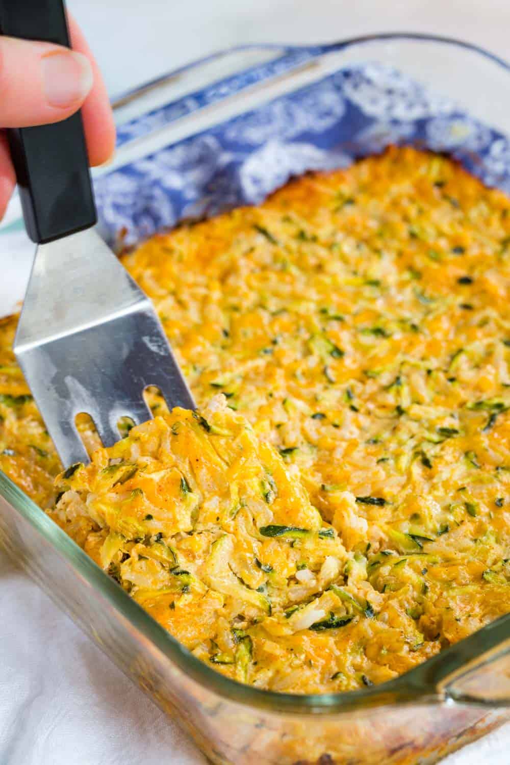 Using a spatula to take a piece of the casserole out of a glass baking dish