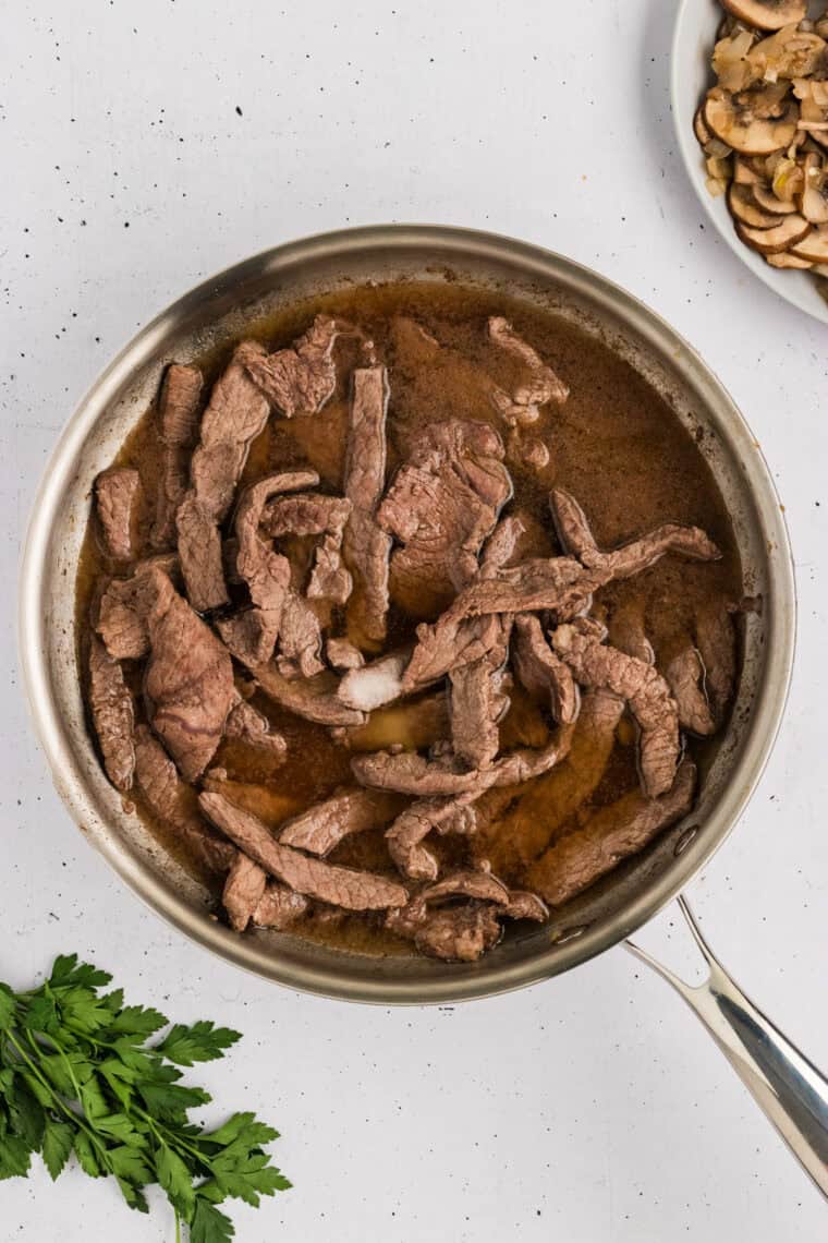 Broth added to the beef in a pan