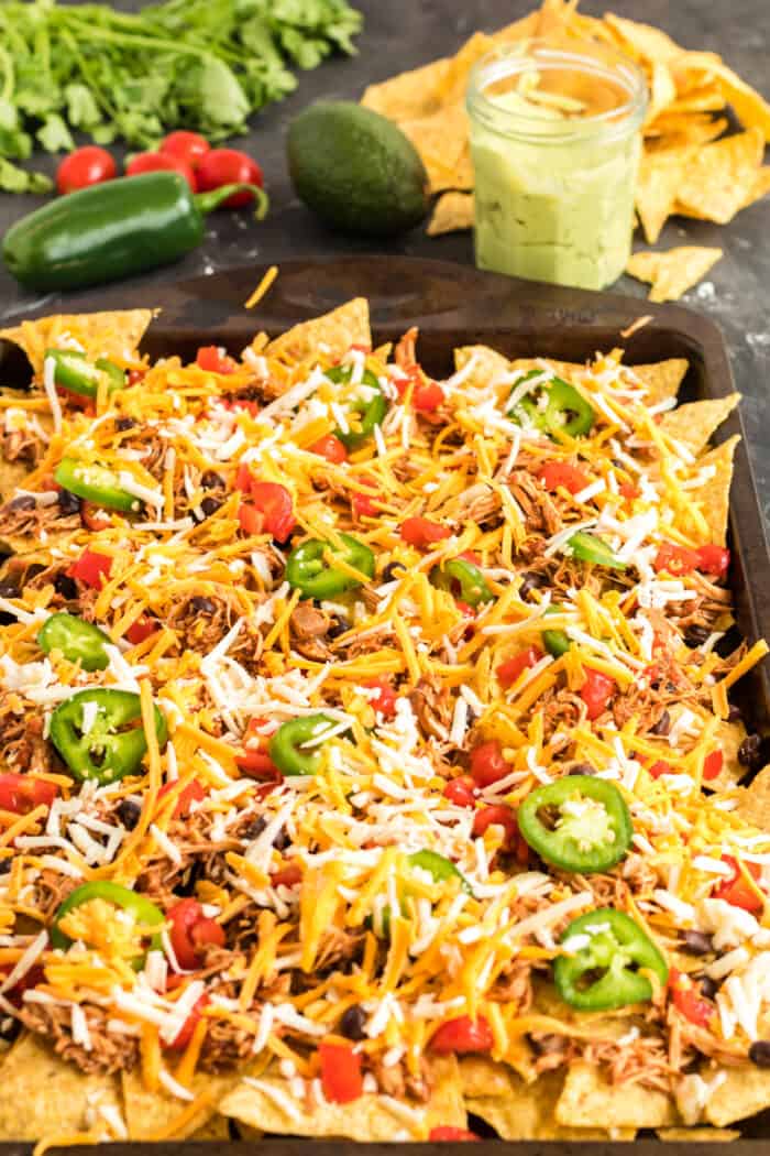 unbaked chicken sheet pan nachos with shredded cheese on top