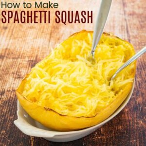 Two forks in a spaghetti squash half with the scraped-out noodles