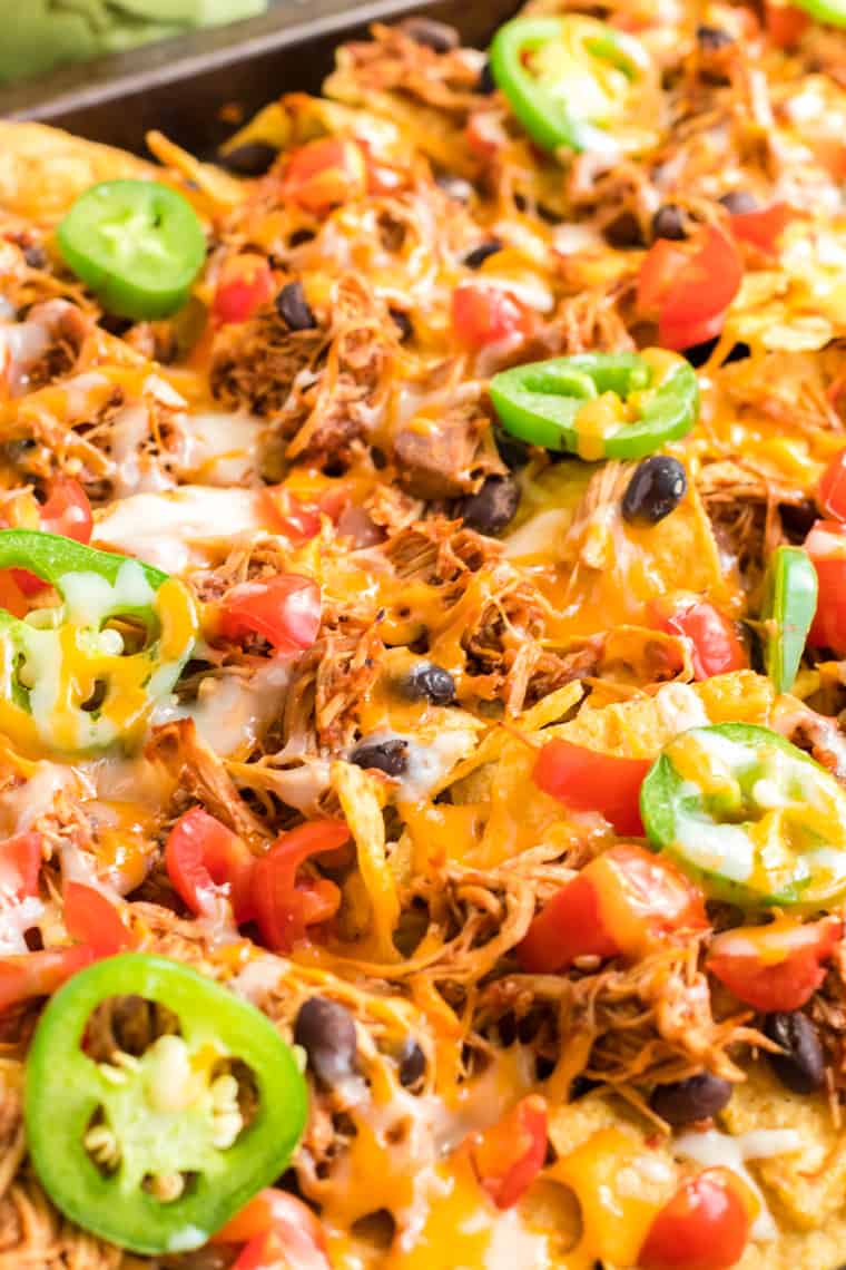 nachos topped with chicken, black beans, tomatoes, jalapenos, and melted cheese