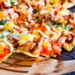 spatula picking up some of the nachos on a sheet pan