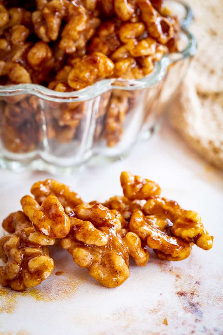 nueces glaseadas con miel y canela en una mesa frente a un tazón