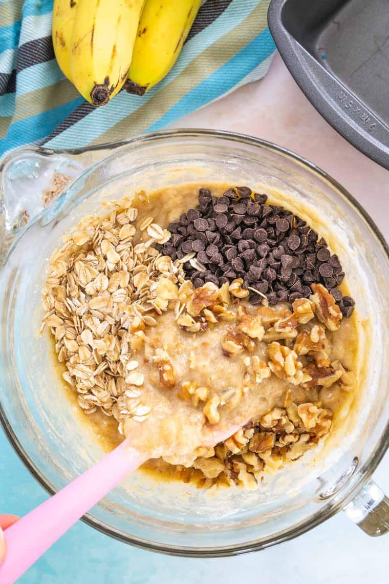 oats, chocolate chips, and walnuts being folded in to batter
