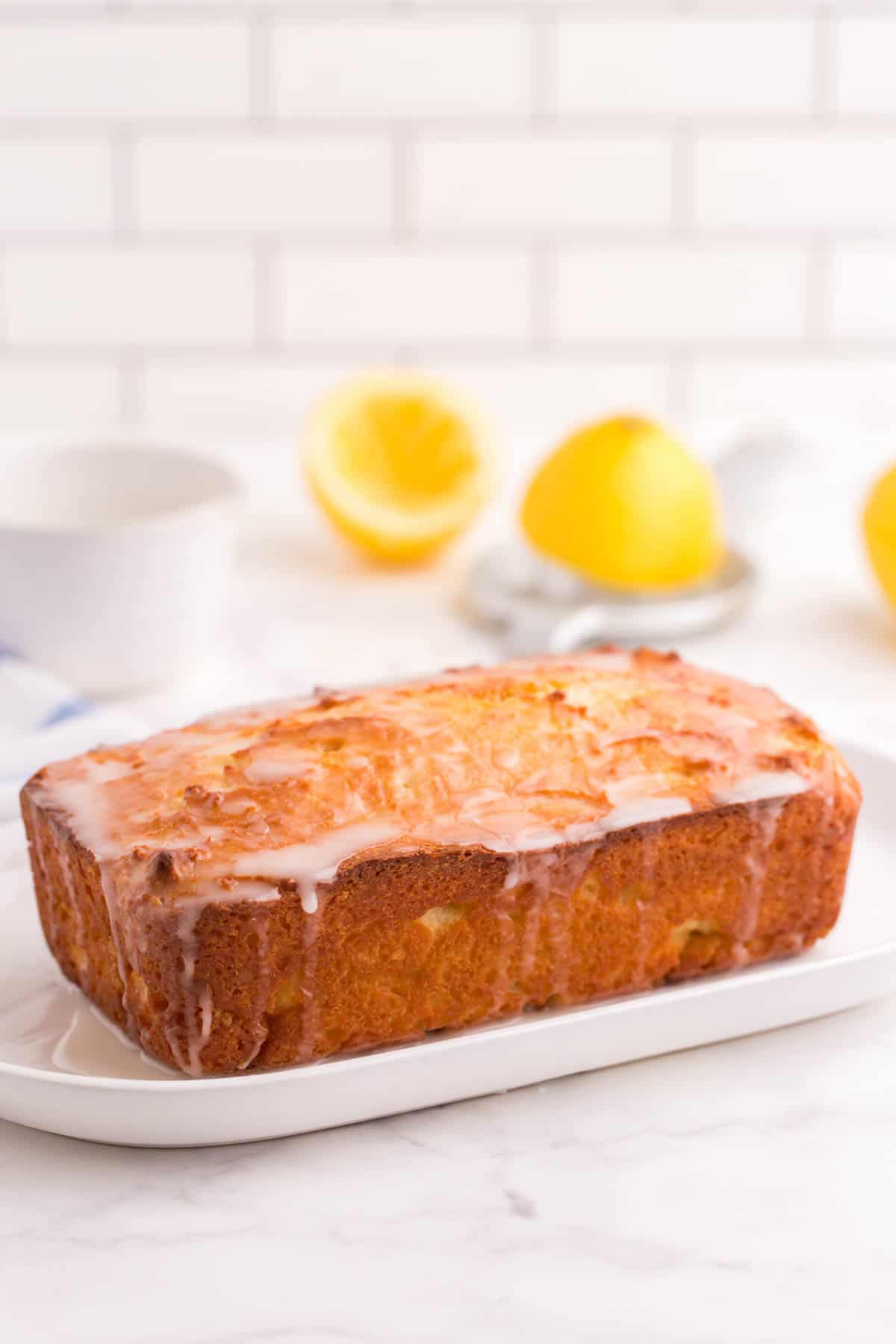 Finished glazed lemon bread on a white platter.