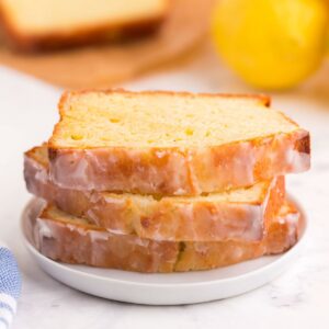 A stack of three slices of gluten free lemon pound cake on a white plate.