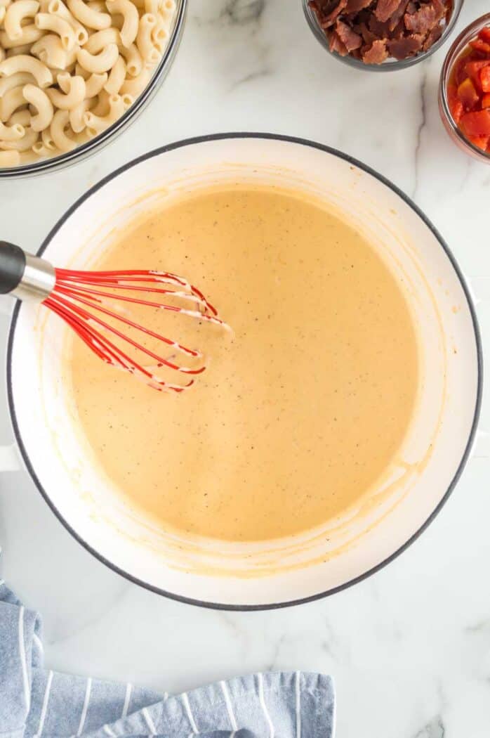 pot of mac and cheese sauce with a whisk