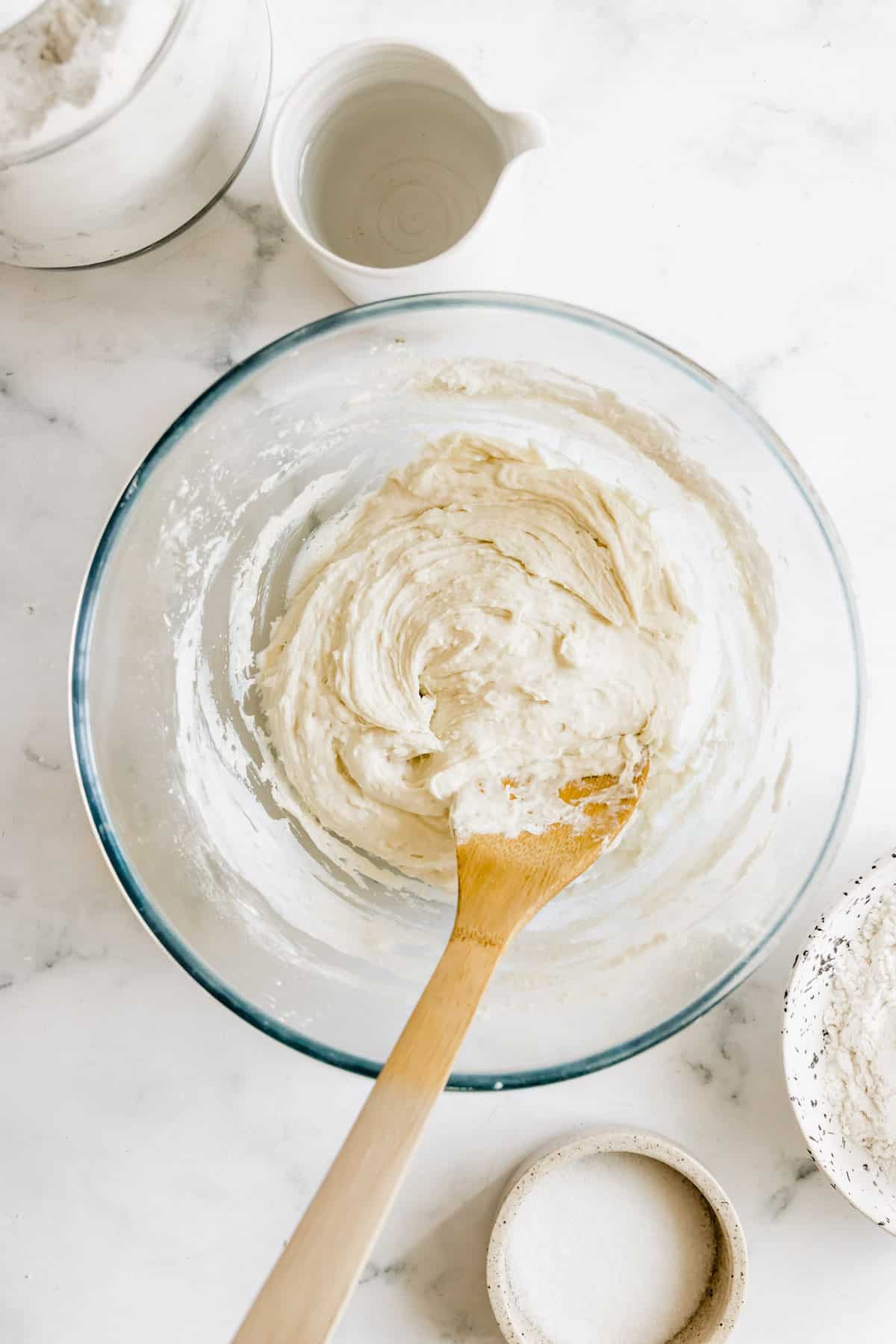 A Wooden Spoon Mixing Pizza Dough in a Large Bowl