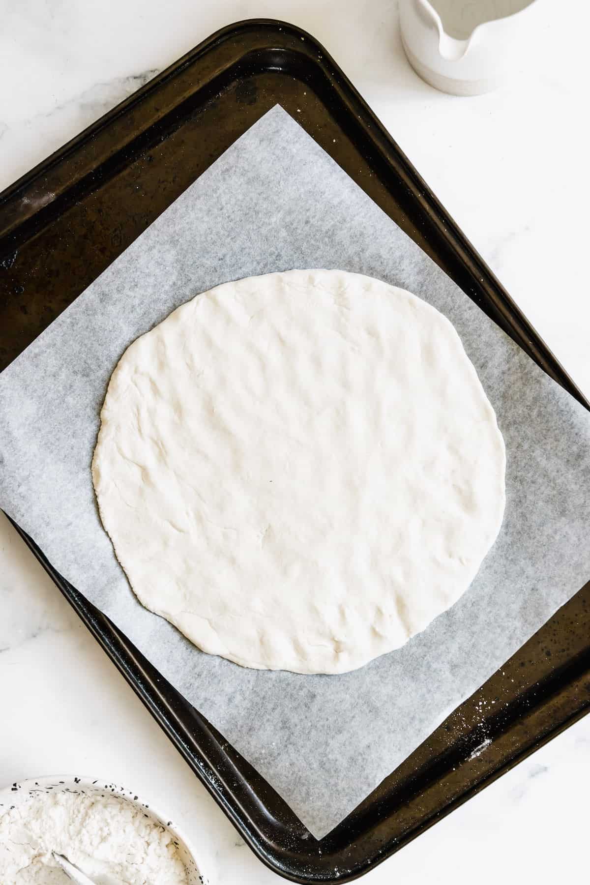 Unbaked Gluten-Free Pizza Dough on a Parchment-Lined Baking Sheet