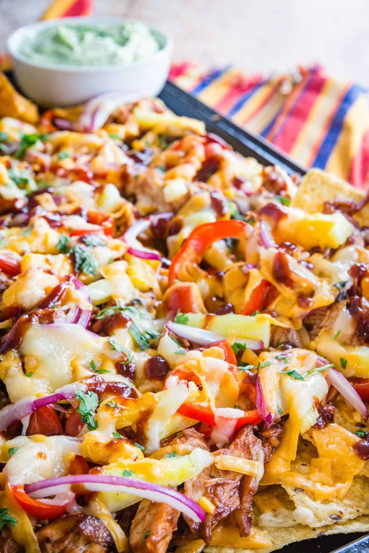 nachos topped with chicken, cheese, red onions, and avocado cream