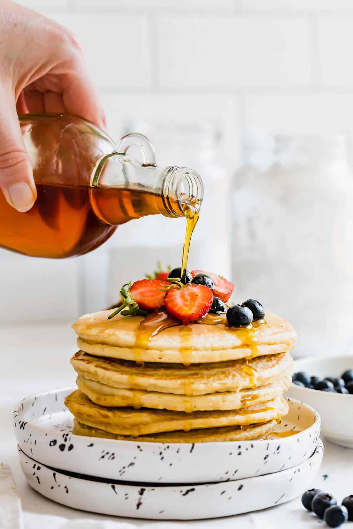 A Stack of Almond Flour Pancakes Topped with Berries and Maple Syrup
