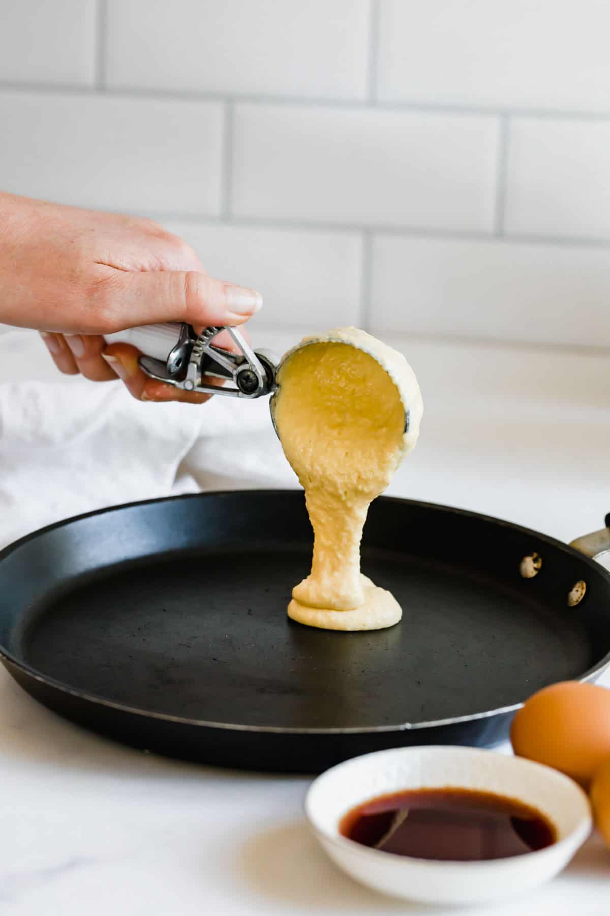 Pancake Batter Being Poured Into a Skillet with an Ice Cream Scoop