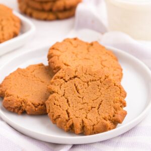 Three peanut butter cookies on a white plate.