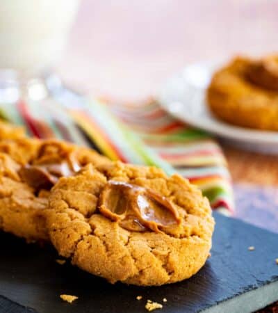 Flourless peanut butter thumbprints cookies with dulce de leche in the middle on a serving platter.