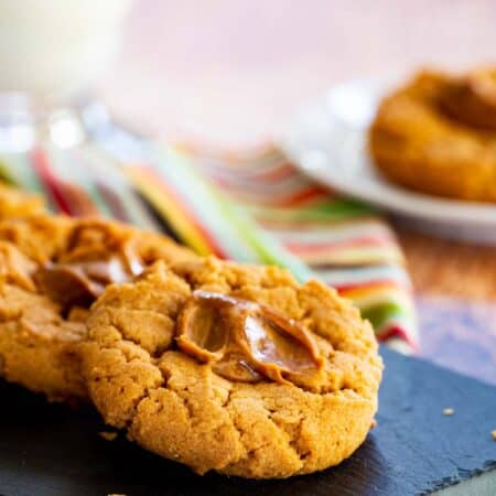 Flourless peanut butter thumbprints cookies with dulce de leche in the middle on a serving platter.