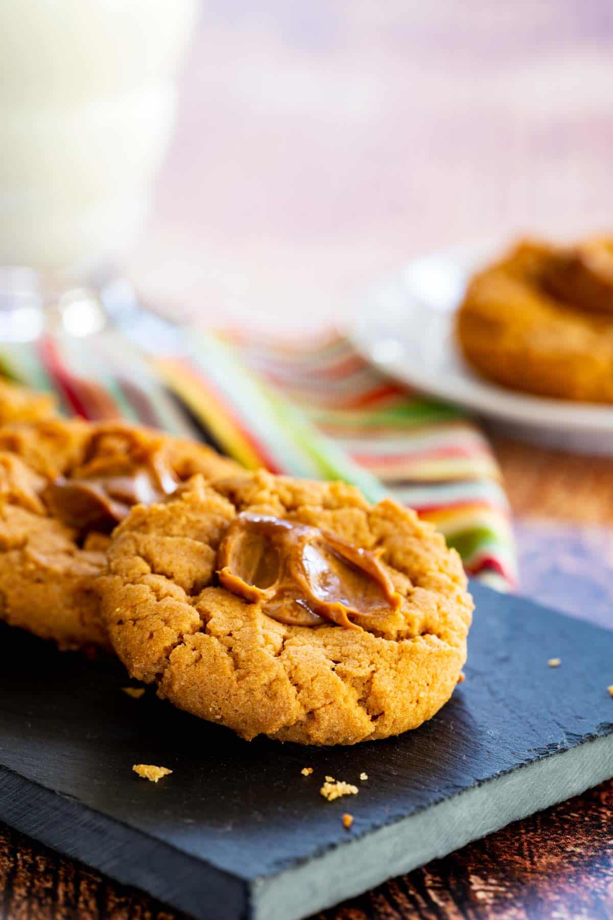 Flourless peanut butter thumbprints cookies with dulce de leche in the middle on a serving platter.